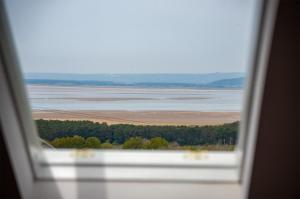 a window with a view of a lake and trees at Highfield - 3 Bedroom Holiday Home - Llanmadoc in Llanmadoc