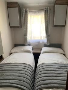 twee bedden in een kleine kamer met een raam bij 36 Glenfinart Caravan Park in Dunoon
