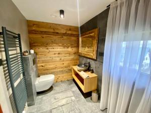ein Badezimmer mit einem weißen WC und einer Holzwand in der Unterkunft Chalupa pod Ořechem in Rokytnice nad Jizerou
