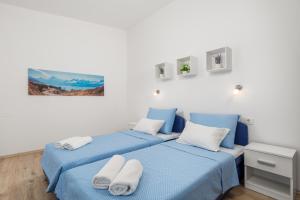 two beds in a white room with blue sheets at Apartment DANI-E.L. in Kastav