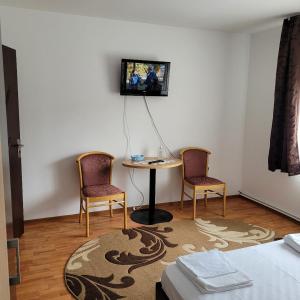 a room with two chairs and a table and a tv on the wall at Casa UILA in Orşova