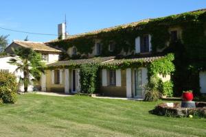 una casa cubierta de hiedra con un patio verde en Les Templiers - Petit BIZERTY 36 pers (Mas privé) - 2 piscines - Salle 200 m² en Saint-Gilles