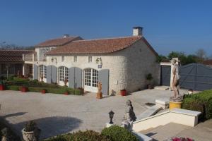 a large white house with a statue in front of it at Villa Charentaise avec piscine privée in Chazelles