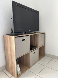 a flat screen tv on a wooden entertainment center at Le Studio 36 à Nîmes, Wifi, Balcon in Nîmes