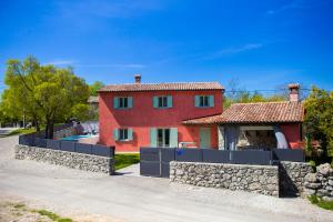 una casa roja con una pared de piedra y una valla en Villa Piano - Učka Nature Park, en Lupoglav