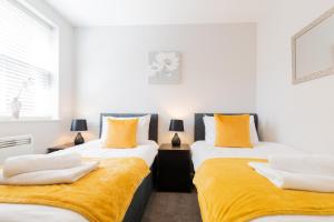 two beds in a room with yellow and white at Velvet 2-bedroom apartment, Brewery Road, Hoddesdon in Hoddesdon