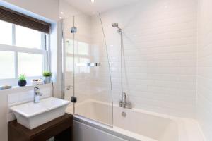 a white bathroom with a sink and a shower at Velvet 2-bedroom apartment, Brewery Road, Hoddesdon in Hoddesdon
