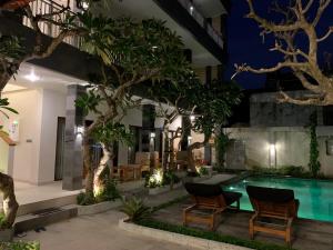 una piscina cubierta por la noche con sillas y árboles en Sandat Living, en Canggu