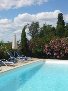 a swimming pool with chairs and an umbrella at Les Templiers - Petit BIZERTY 36 pers (Mas privé) - 2 piscines - Salle 200 m² in Saint-Gilles