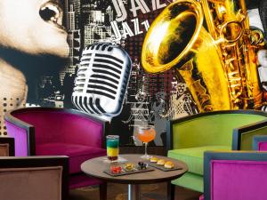un bar con sassofono, drink e tavolo di Hôtel Roi Soleil Prestige Plaisir - St Quentin a Plaisir