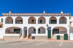 a white building with balconies and a parking lot at Tramontana 113 P1 by 3VILLAS in Fornells