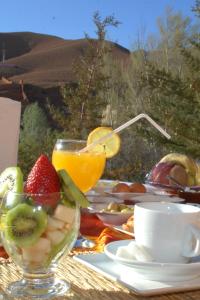a table with a bowl of fruit and a cup of orange juice at Dar Mezyana Dades in Aït Idaïr