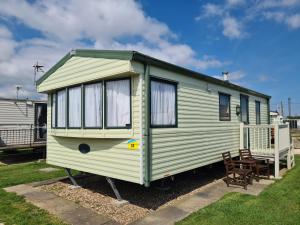 a green and white tiny house with a chair at 6 Berth Sealands Ingoldmells Free WIFI Westmorland SL in Ingoldmells
