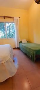 two beds in a room with a window at Las Casitas, cabañas & suites in Pincén