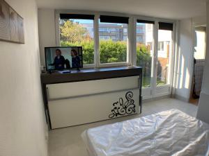 um quarto com uma televisão e uma cama num quarto com janelas em Résidence About Malo RDC avec jardin lumineux à 2 pas de la plage em Dunkerque