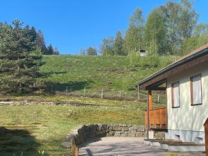 un edificio con una pared de piedra junto a un campo en Le Bucheron au cœur du massif des Vosges 3 étoiles, en Gérardmer