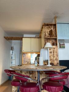a kitchen with a counter with red chairs around it at Le Studio Victoria II -Mon Desert Village -27m2 in Nancy