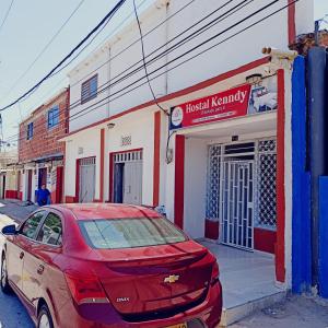 ein rotes Auto, das vor einem Gebäude parkt in der Unterkunft HOSTAL KENNDY in Valledupar
