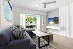 a living room with a blue couch and a table at Beach Club Port Douglas Luxury Apartments in Port Douglas