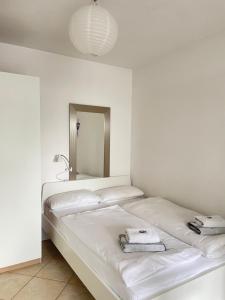 a white bedroom with two beds and a mirror at Fewo Petershausen in Konstanz