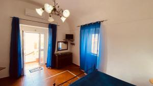 a room with blue drapes and a bed and a television at Casa Ninetta - Immobilevante in Ponza