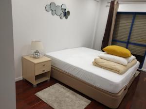 ein Bett mit gelbem Kissen und einem Nachttisch in der Unterkunft Setúbal Health Beach in Setúbal