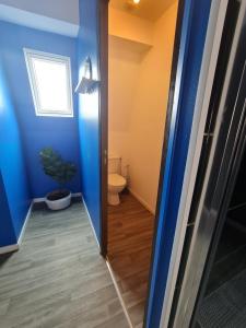een badkamer met een toilet en een blauwe muur bij NG SuiteHome - Lille I Roubaix Centre I 121 - Gamer - Arcade de jeux - Netflix - Wifi in Roubaix