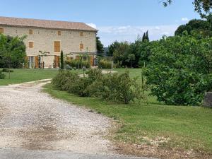 Un camino de grava frente a un gran edificio en LA BERGERIE, en Domessargues