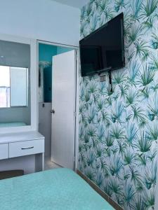 a bedroom with a wall with a mural of palm trees at Hermoso mini departamento c/ entrada independiente in Piura