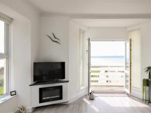 a white living room with a television and a large window at Sea Breeze in Marazion