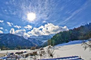 um campo coberto de neve com o sol no céu em Ferienwohnungen Wanderparadies Bauernhof em Aschau im Chiemgau