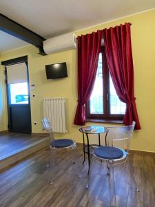 2 sillas y 2 mesas en una habitación con cortinas rojas en Atene del Canavese, en San Giorgio Canavese