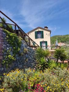 a house on the side of a stone wall with flowers at La Sorgente Apartment with private pool in Calice Ligure