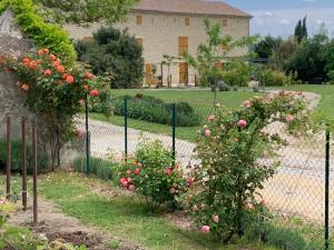 una cerca frente a una casa con rosas rosas en LA BERGERIE, en Domessargues