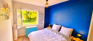 Dormitorio azul con cama y ventana en Le Douillet par Picardie Homes, en Crouy