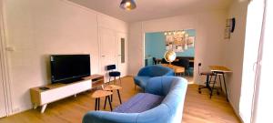 uma sala de estar com duas cadeiras azuis e uma televisão em Le Douillet par Picardie Homes em Crouy