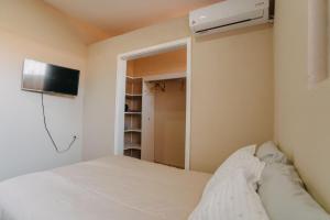 1 dormitorio con 1 cama y TV en la pared en Casa Primavera/ Valle de Guadalupe, en Valle de Guadalupe
