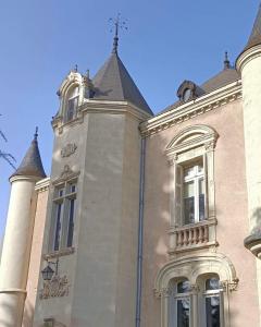 un bâtiment avec une tour d'horloge en haut dans l'établissement Le Château de Leugny, à Oiron