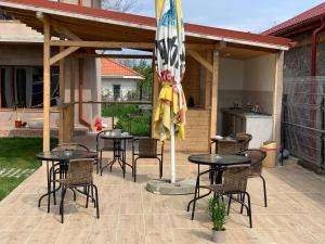 a patio with tables and chairs and an umbrella at Casa Ella in 2 Mai