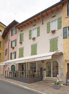 un edificio con ventanas con persianas verdes y mesas al aire libre en B&B San Rocco en Gargnano