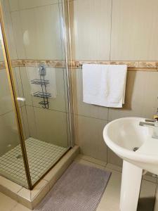 ein Bad mit einer Dusche und einem Waschbecken in der Unterkunft E & P Cave in Swakopmund