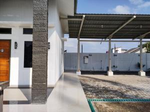a white house with a wooden door and a fence at Cahaya kos putri in Banda Aceh +5 photos