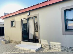 uma pequena casa branca com uma porta preta em E & P Cave em Swakopmund