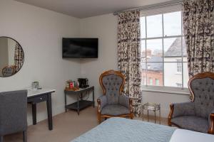a bedroom with a bed and two chairs and a window at The Grosvenor Arms in Shaftesbury