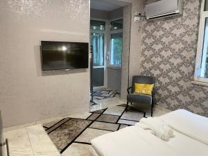 De Luxe Studio Burgas, City Center في مدينة بورغاس: غرفة نوم مع تلفزيون على الحائط وكرسي