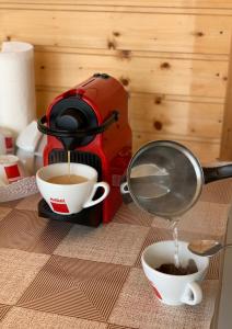 a coffee maker pouring coffee into two cups on a table at Casa Ella in 2 Mai +5 photos