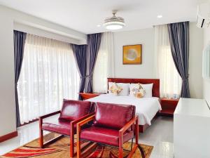 um quarto de hotel com uma cama e duas cadeiras em My Key Premier Palace Private Villa em Siem Reap