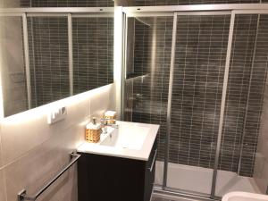 a bathroom with a sink and a shower with a mirror at Yuhom casas con alma Galera 2º in A Coruña +7 photos