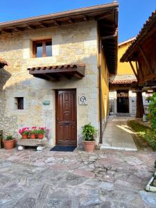 a stone building with a wooden door and potted plants at La Casina de la Arquera in Llanes