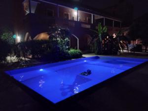 a swimming pool with blue lighting in a yard at night at Begue Pokai in Toubab Dialaw